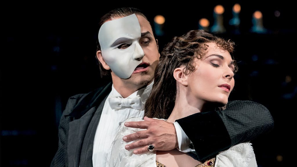From the Phantom of the Opera, the Phantom stands with an arm around Christine's neck