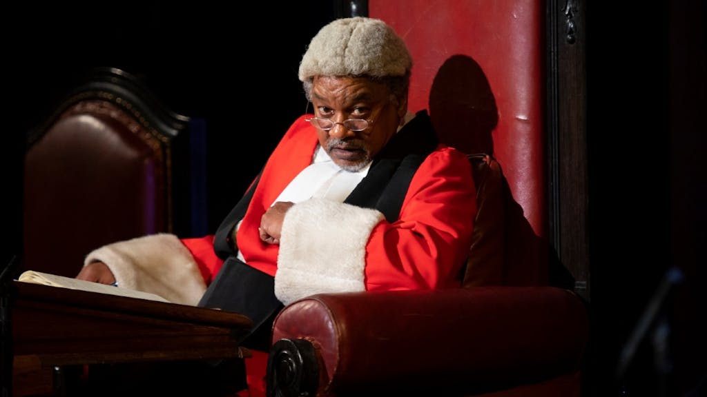 From Witness for the Prosecution, a man sitting in a large maroon chair with a red jacket on