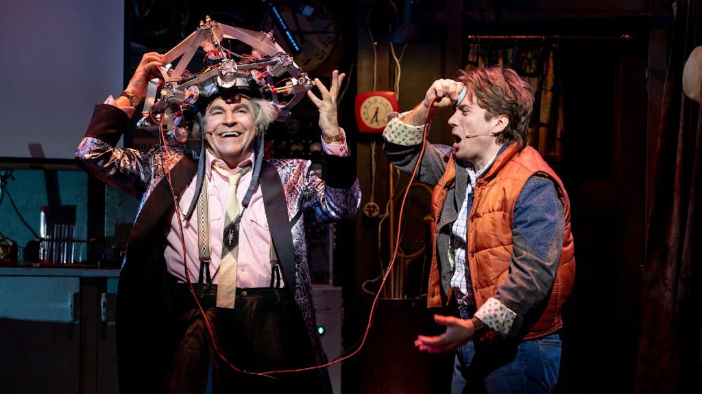 Doc Brown and Marty McFly in Back to the Future. Doc has a wacky hat on, and Marty is holding a wire attached to it up to his forehead