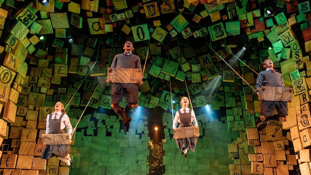 Four cast members of Matilda the Musical on swings